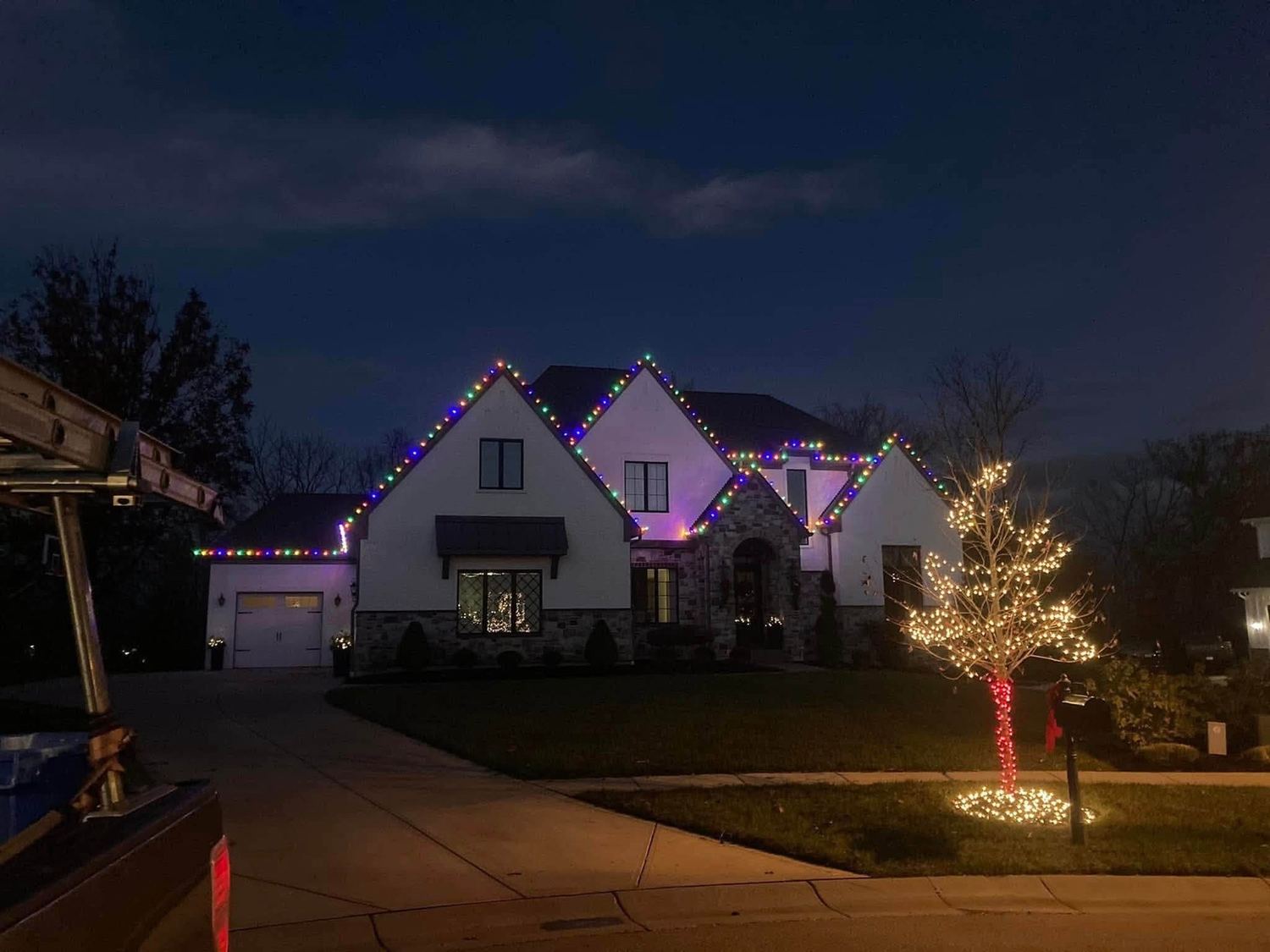Multicolor roofline with a wrapped tree out front — Christmas light installation in Greater Cincinnati by Mike’s Cincinnati Christmas Lights